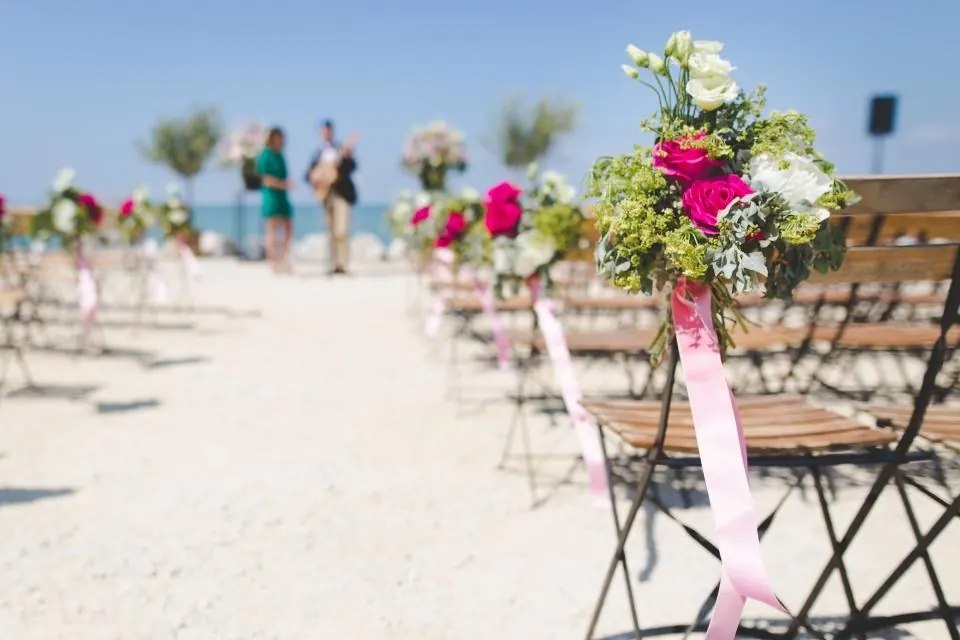 Pasillo de sillas con flores sobre la arena para una ceremonia en la Costa del Sol