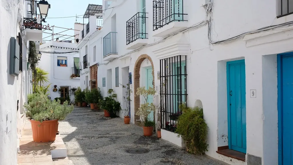 Calle encalada de Frigiliana con puertas azules y macetas
