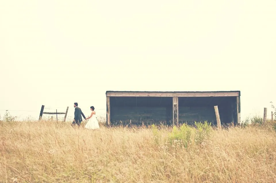 Pareja de novios paseando por un campo dorado junto a una finca de boda en Málaga